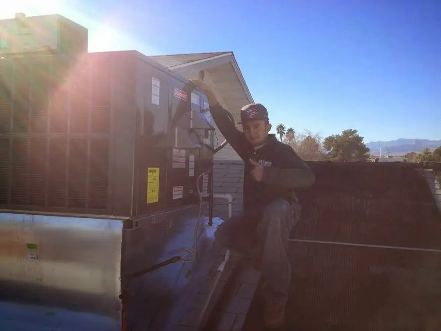 HVAC technician performing Heat Pump Repair on a rooftop unit in Knik-Fairview